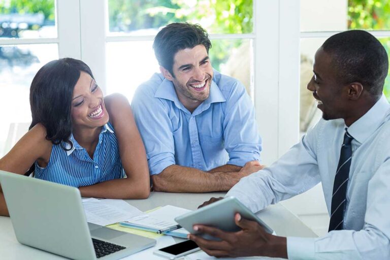 A young couple reviews a home inspection report while standing in a bright, unfurnished living room.